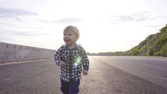 A little 2 year old baby boy is walking on sunset. Child make his first steps outdoor