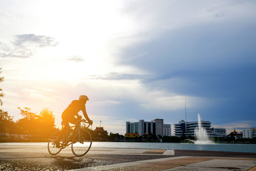 Fototapeta premium Cyclist in motion on background beautiful sunset with silhouette. Ride on bike on the road . Man ride bicycle in the road.silhouette of cyclist in summer concept. Cyclist in city park.