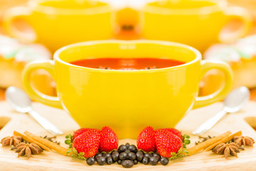 Espresso coffee in a yellow cup, with a strawberry fruit, grapes and cinnamon in front, in white background