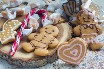 Fototapeta na wymiar Sweet gifts for holiydays. Homemade christmas gingerbread cookies and caramel candies on board, horizontal