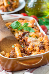 Ziti bolognese in a baking dish, pasta casserole with minced meat, tomato sauce and cheese, vertical