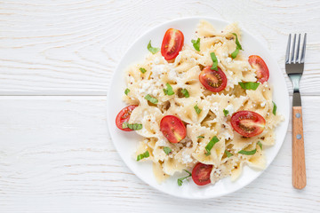 Pasta salad with tie pasta, feta cheese, cherry tomatoes, mustard and basil, top view, copy space