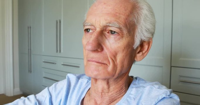 Senior man sitting in wheelchair looking through window in bedroom
