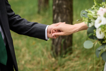 Bride and groom walking and holding hands in the forest on nature