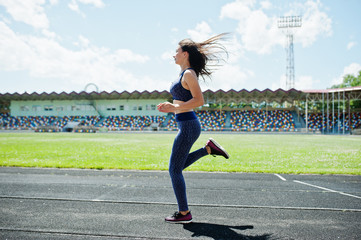 Fototapeta premium Portrait of a strong fit girl in sportswear running in the stadium.