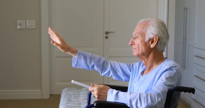 Senior man in wheelchair waving at home