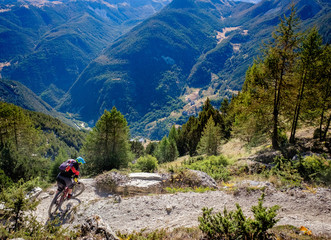 Fototapeta na wymiar mountain biker turning a corner high above a valley in the Alps