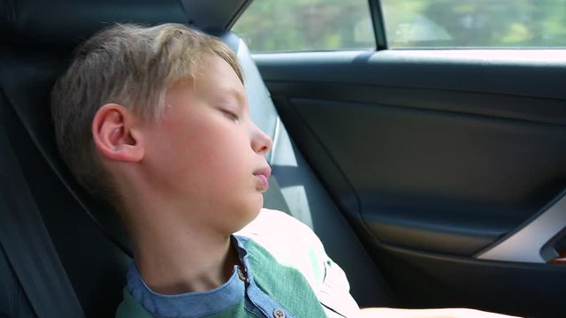 Closeup profile portrait of white handsome child of 10 years old sleeping in car on back seat. Real time full hd  video footage.