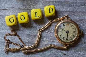 Gold Buchstabenwürfel und Uhr auf grauem Holz visualisierung