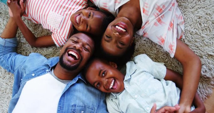 Portrait of happy parents and kids lying on rug