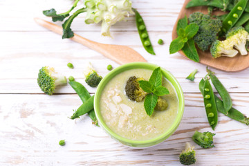 Broccoli and green peas puree soup decorated with mint