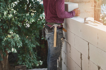 Mason worker building exterior walls, Industrial bricklayer installing bricks on construction site