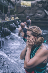 European woman at Pura Tirta Empul temple during a religious ceremony in Tampa, Bali, Indonesia.