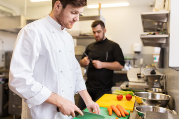 chef and cook cooking food at restaurant kitchen