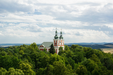 Cvilin, Krnov, Czech Republic / Czechia - church on the top of the hill. Spires and towers are surrounded by green nature. Landscape in the background.