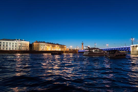 Yachts near palace bridge and Vasilievsky Island at night in St. Petersburg, Russia