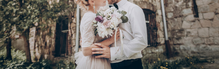 stylish wedding couple with bouquet. modern bride and groom holding fashionable bouquet at old ...