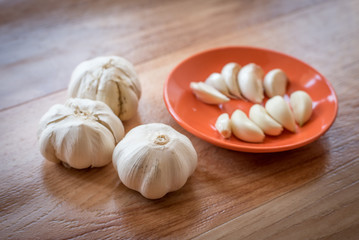 White garlic bulb in an orange plate and leaves of green parsley
