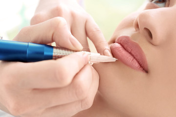 Obraz na płótnie Canvas Young woman having permanent makeup on lips in beautician salon
