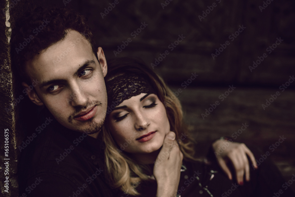 Wall mural stylish gypsy couple in love embracing in evening city street at old building. woman and man hugging, romantic french atmospheric moment. love mood. modern bride and groom