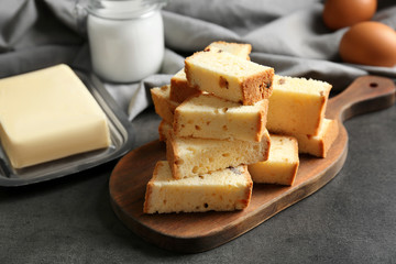 Wooden board with delicious sliced butter cake on table
