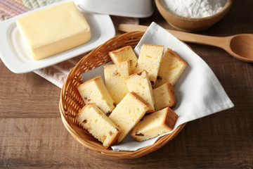 Wicker basket with delicious sliced butter cake on wooden table