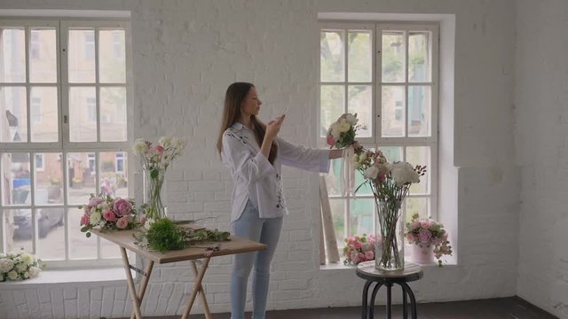Young florist girl finished making bouquet and making pictures