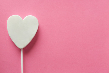 Tasty candy in shape of heart on color background