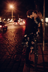 Sexy couple kissing outdoors in the street, two lovers kiss in night street in Paris on their honeymoon, passion concept