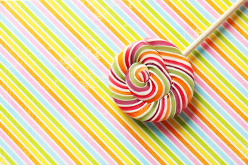 Fototapeta na wymiar Tasty spiral candy on patterned color background