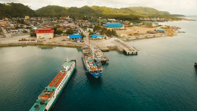 Cargo and passenger port with barges and cargo ships on tropical island. Aerial view:passenger ferry terminal Dapa city .Ferries for transport vehicles and passengers in the port. Philippines, Siargao