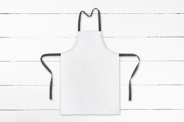 Blank white apron on white wooden background. Top view