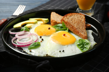 Delicious over easy eggs with toasts, onion and avocado on kitchen table