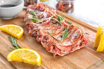 Raw pork ribs and lemon slices on wooden board, closeup