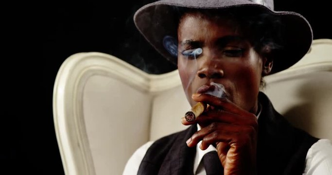 Androgynous man smoking cigar on armchair