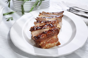 Plate with delicious pork ribs on wooden table, closeup