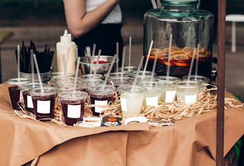 strawberry and lime lemonade, space for text. street food festival. drink bar at reception, catering outdoors. summer picnic. colorful drinks in plastic cups with straws