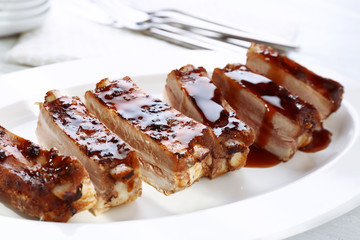 Delicious pork ribs with soy sauce on plate, closeup