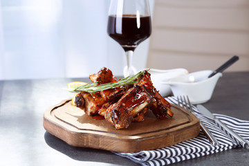 Wooden board with delicious pork ribs on table