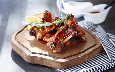 Wooden board with delicious pork ribs on table