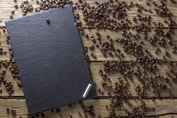 Obraz premium Coffee beans and chalkboard with chalk on background from wooden planks. Top view. Mockup