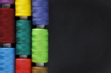 Set of colorful spools of thread on black background. Mockup. Top view. Flat lay