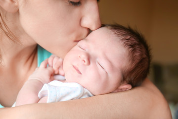 Obraz na płótnie Canvas Happy young woman kissing her newborn baby boy, closeup