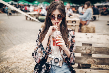 stylish hipster woman drinking lemonade. cool boho girl in denim and bohemian clothes, holding...