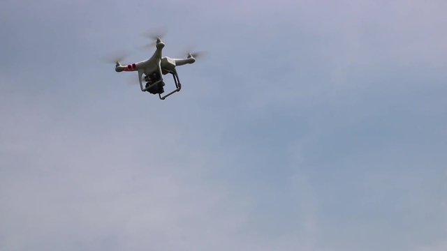 Small drone flying outside, isolated on a blue sky. Copy space on the right.