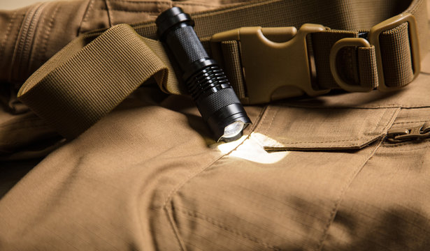 Black torch and buckle on brown textile.