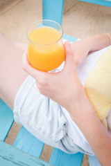 Close-up of woman hands holding glass of orange juice outdoor