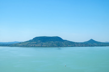 sailboat on water, fameus Badacsony hill in background - summertime and vacation at Balaton lake