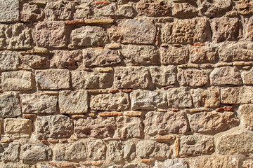 medieval stone wall of old building in sunny day