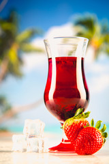 Cold tasty drink on a beach with palms in background